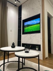 a living room with two tables and a tv on a wall at Green Apartment&Spa in Zlatibor