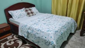 a bed with a blue and white comforter at Carolina Lodging Apartment - Free & Fast Wi-Fi in Douala