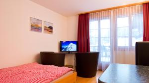 a room with a table and a television and a window at MOM - Alpine Boutique Apartments, Chalet Fagus, Terrace Studio in Grindelwald