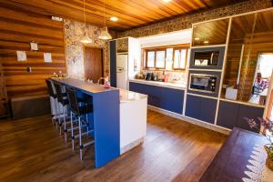a kitchen with a blue island with stools at Chalé Família - Sítio Vale Encantado in Treviso +21 photos