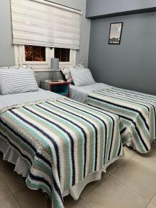 two beds with striped blankets in a room with a window at Casa hermosa piscina con parrilla in Victoria