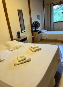 a bedroom with two beds and two towels on a bed at Chalé nas Árvores in São Francisco Xavier