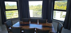 a dining room with a table and chairs and windows at Villa Pura Vida - All Inclusive in Ocotal