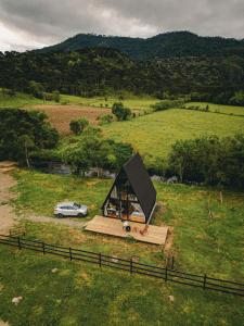 a small house in a field with a car at Cabana Uruma in Urubici