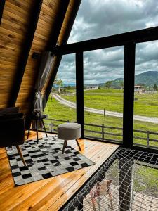 a room with a view of a field from a porch at Cabana Uruma in Urubici +6 photos