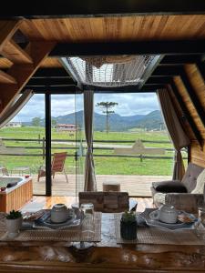 a living room with a table and a view of a field at Cabana Uruma in Urubici