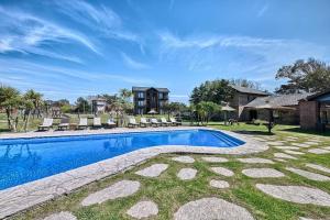 a swimming pool in a yard with chairs and a house at Marina Green Club, Tres ambientes in Villa Gesell +6 photos