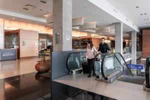 a man and woman standing next to a car at an airport at Marriott Montreal Airport In-Terminal Hotel in Dorval
