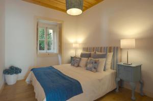 een slaapkamer met een bed met een blauwe deken en een raam bij Portas do Teatro Apartments in Lissabon