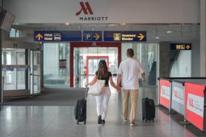 a man and woman walking through an airport with their luggage at Marriott Montreal Airport In-Terminal Hotel in Dorval