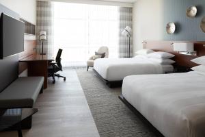 a hotel room with two beds and a desk at Marriott Montreal Airport In-Terminal Hotel in Dorval