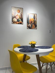a dining room with a table and yellow chairs at Impera House Ar nos dois quartos in Imperatriz