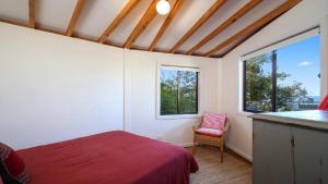 a bedroom with a red bed and a window at 'The Yurt' by HolidayCo in Hardys Bay
