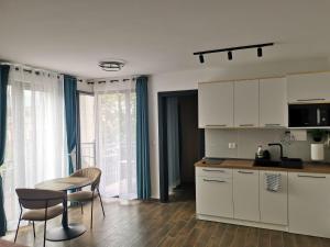 a kitchen with white cabinets and a table and chairs at LILLY apartman in Vrnjačka Banja