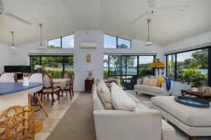 a living room with white furniture and large windows at Rangimarie - Paihia Holiday Home in Paihia