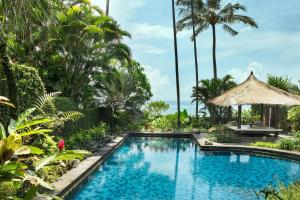 a swimming pool in a resort with palm trees at Sheraton Senggigi Beach Resort in Senggigi