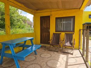 a blue picnic table on the porch of a yellow house at Mirador del Diablo in Punta Del Diablo +10 photos