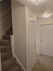 a hallway with stairs and a white door at Romford Luxe Home in Goodmayes