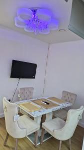 a dining room table with chairs and a chandelier at Romford Luxe Home in Goodmayes