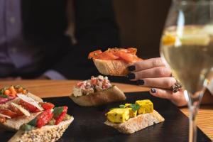a woman holding a glass of wine next to sandwiches at Sheraton Cascais Resort - Hotel & Residences in Cascais