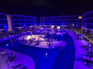 ein großes Schwimmbecken bei Nacht mit violetten Lichtern in der Unterkunft Malia Experience-Muro Alto e Porto de Galinhas in Ipojuca