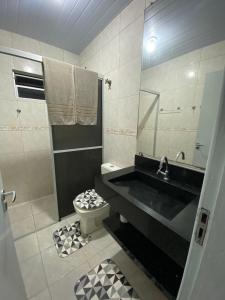 une salle de bain avec un lavabo noir et des toilettes dans l'établissement Casa perto da praia em Itapema, à Itapema