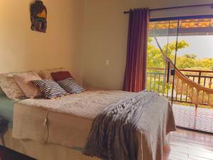 una camera da letto con letto con cuscini e balcone di Claruá Chalés - Loft Caju - Romântico & Charmoso em Cavalcante Chap dos Veadeiros a Cavalcante