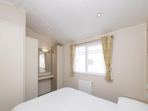 a bedroom with a white bed and a window at Suncrest Plus Caravan by Belvilla in Looe