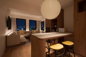a kitchen with a bar with stools and a living room at the b osaka-shinsekai in Osaka