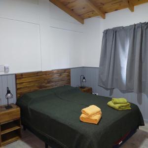 a bedroom with a green bed with two yellow towels on it at El Cardon in Sierra de la Ventana