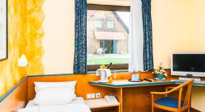 1 dormitorio con cama, escritorio y ventana en Landhotel Mappacher Hof, en Bruck in der Oberpfalz