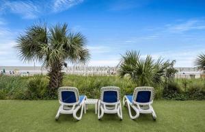 tres sillas sentadas en el césped cerca de la playa en Wow! Oceanview 3 bedroom condo! Pool & private balcony, en Myrtle Beach