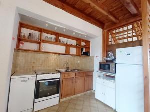 Una cocina con electrodomésticos blancos y gabinetes de madera. en Maison familiale près plage St Brevin, animaux admis, parking privé - FR-1-364-40, en Saint-Brevin-les-Pins