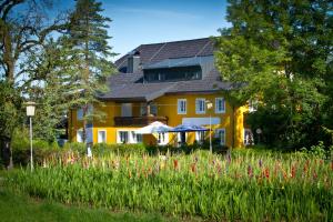 a yellow house with a field of flowers at Landgasthof zum Betenmacher in Thalgau