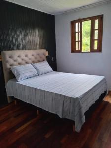 un letto grande in una camera da letto con finestra di Sitio dos pinhais a Pelotas