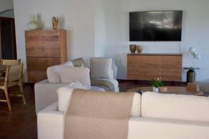 a living room with two white couches and a tv at Villa Camélia in Oyster Pond