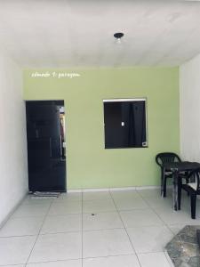 a room with a wall with a tv and two chairs at Chalé Di vino in Porto Seguro