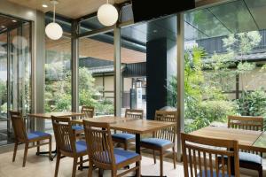 a restaurant with wooden tables and chairs and large windows at Four Points Flex by Sheraton Kyoto Oike in Kyoto