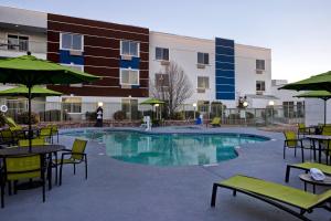 a pool with tables and chairs and a building at SpringHill Suites by Marriott Las Cruces in Las Cruces