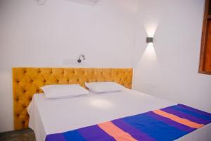 a bedroom with a white bed with a wooden headboard at Hill Top Heaven in Hikkaduwa