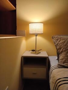 a lamp on a night stand next to a bed at Departamento Letty I - Con Cochera in San Salvador de Jujuy