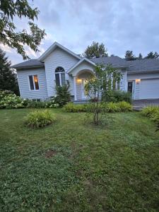 a white house with a lawn in front of it at Villa Des Petits Bonheurs in Lac-Simon +16 photos