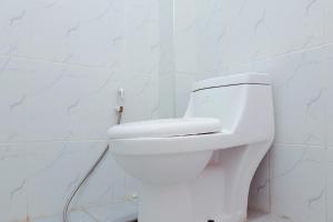 a bathroom with a white toilet in a white wall at Urbanview Hotel at Guest House Bukit Sion Bengkulu in Bengkulu