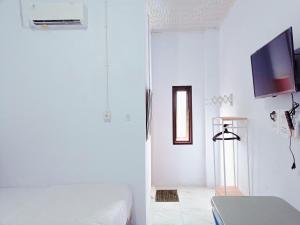 a white room with a bed and a television at Urbanview Hotel at Guest House Bukit Sion Bengkulu in Bengkulu +21 photos