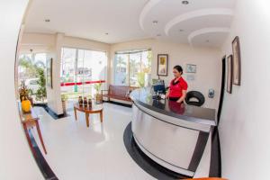 a woman sitting at a desk in a lobby at Hotel Oceania in Eunápolis