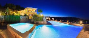 a house with a swimming pool at night at Villa Akros and Suites in Keri
