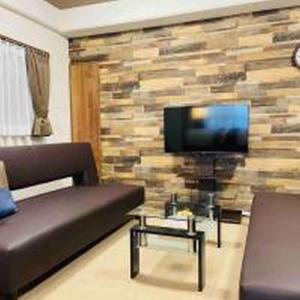 - un salon avec un canapé et une télévision sur un mur en pierre dans l'établissement Alzate Uemachi 301 アルザーテ上町 301, à Osaka