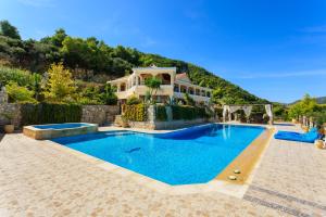 a villa with a swimming pool in front of a house at Villa Akros and Suites in Keri