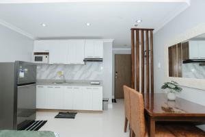 a kitchen with white cabinets and a wooden table at Condo18k Beside Mactan Newtown in Lapu Lapu City