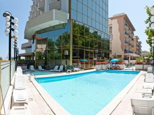 a large swimming pool with chairs and a building at Hotel Diplomat Palace in Rimini